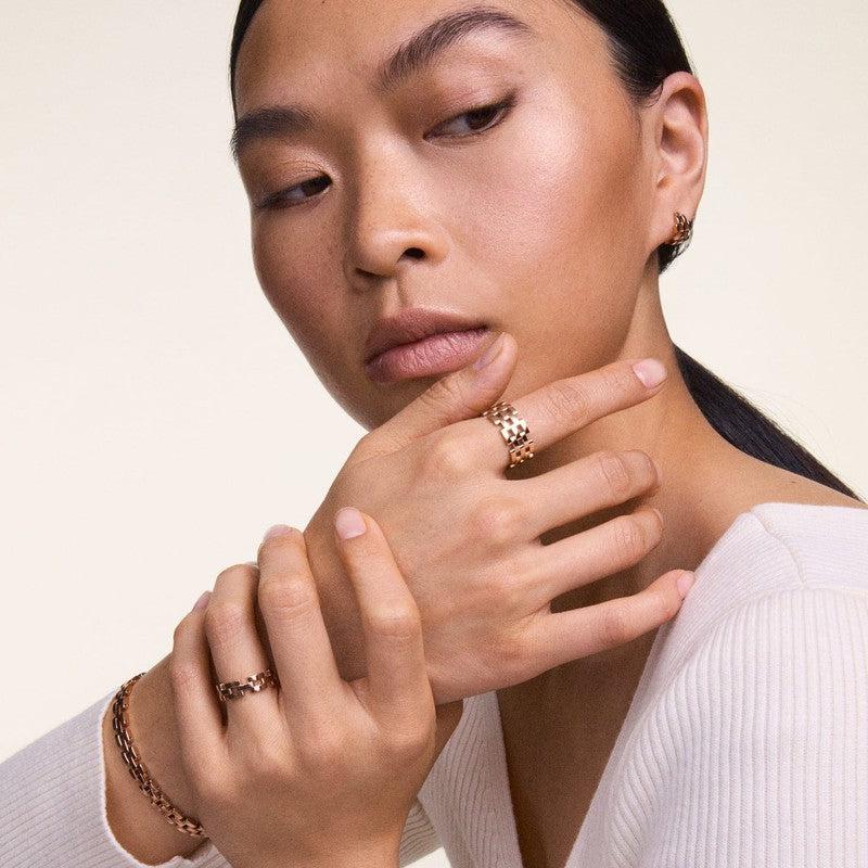 Elegant Daniel Wellington 5-Link ring in polished rose gold stainless steel worn on a finger for a sophisticated look.