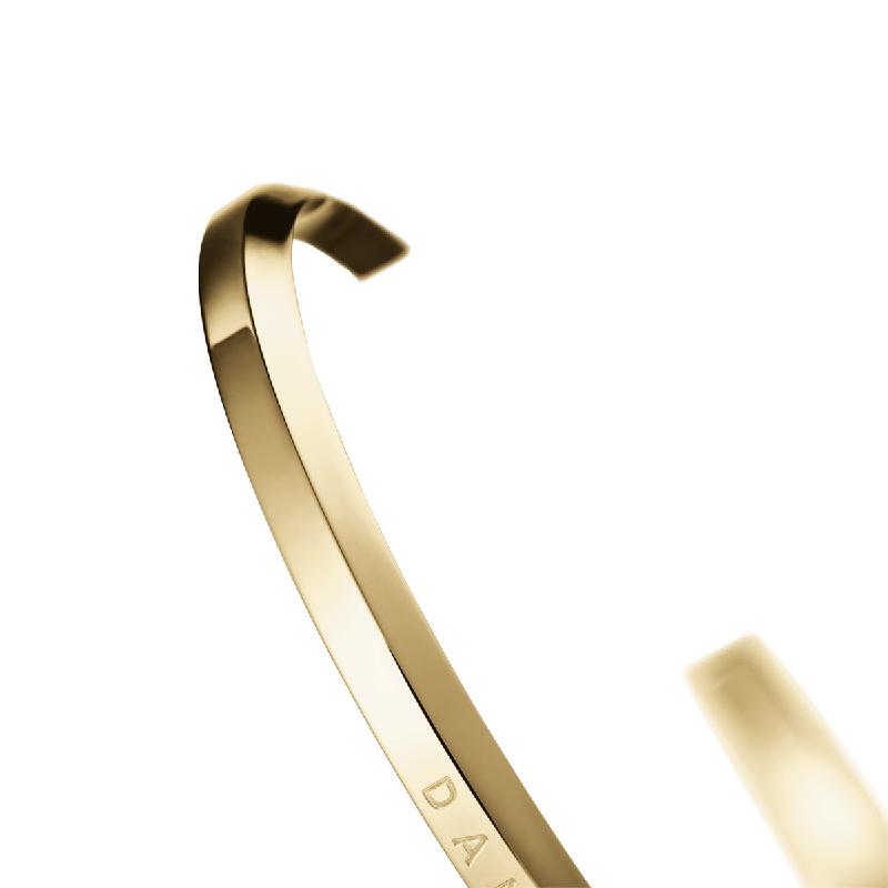 Minimalist Daniel Wellington gold stainless steel cuff bracelet with elegant, polished finish and engraved logo.