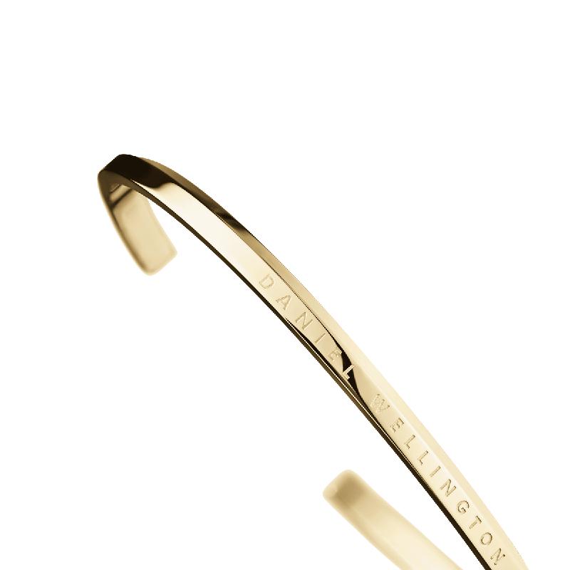 Minimalist Daniel Wellington gold cuff bangle crafted from polished double-plated stainless steel with engraved logo.
