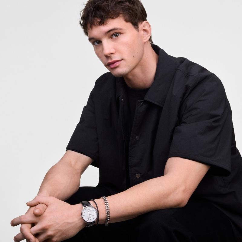 Man wearing a 40mm Daniel Wellington Classic Multi-Eye Sheffield watch with a silver case and black leather strap.