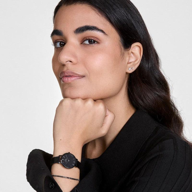 Model wearing a Daniel Wellington gold-tone crystal tennis bracelet paired with a sleek black watch.