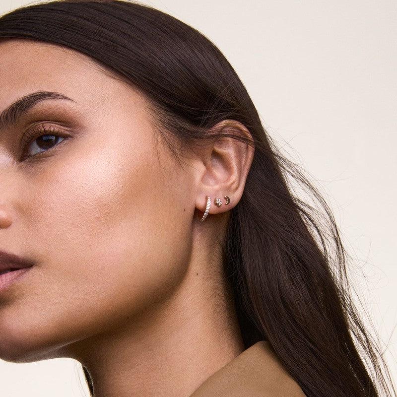Elegant 13.6mm rose gold stainless steel hoop earrings featuring a sparkling claw-set crystal design on a model.