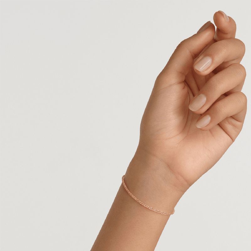 Elegant Daniel Wellington Elan twisted chain bracelet in gold-plated stainless steel worn on a wrist.