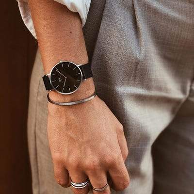 Daniel Wellington Petite Ashfield 36mm watch with a sleek black dial and matte black mesh strap in silver stainless steel.