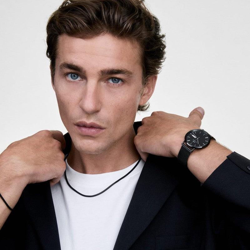 Unisex Daniel Wellington Tide mesh necklace in black stainless steel, worn with a matching black mesh strap watch.