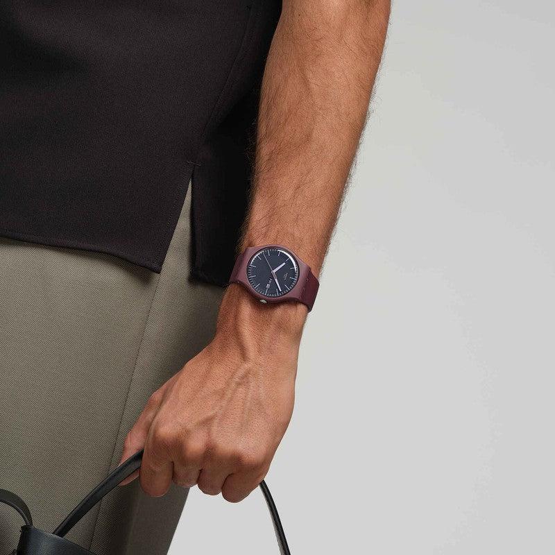 Swatch Burgundy Berry watch with a matte biosourced case, dark brown dial, and comfortable matching burgundy strap on wrist.