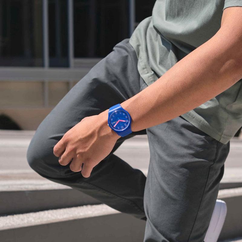 Swatch Cobalt Disco biosourced blue watch with pink glow-in-the-dark hands on a matte silicone strap.