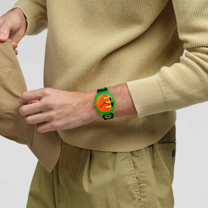 Swatch Neon Rider watch with a vibrant neon dial, green biosourced case, and black strap with colorful 80s-inspired accents.