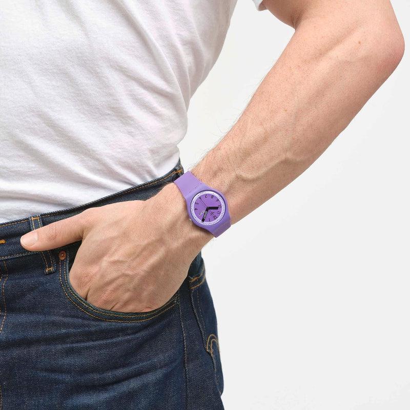 Swatch Proudly Violet watch with a purple biosourced case and strap worn on a wrist, featuring a vibrant violet dial.