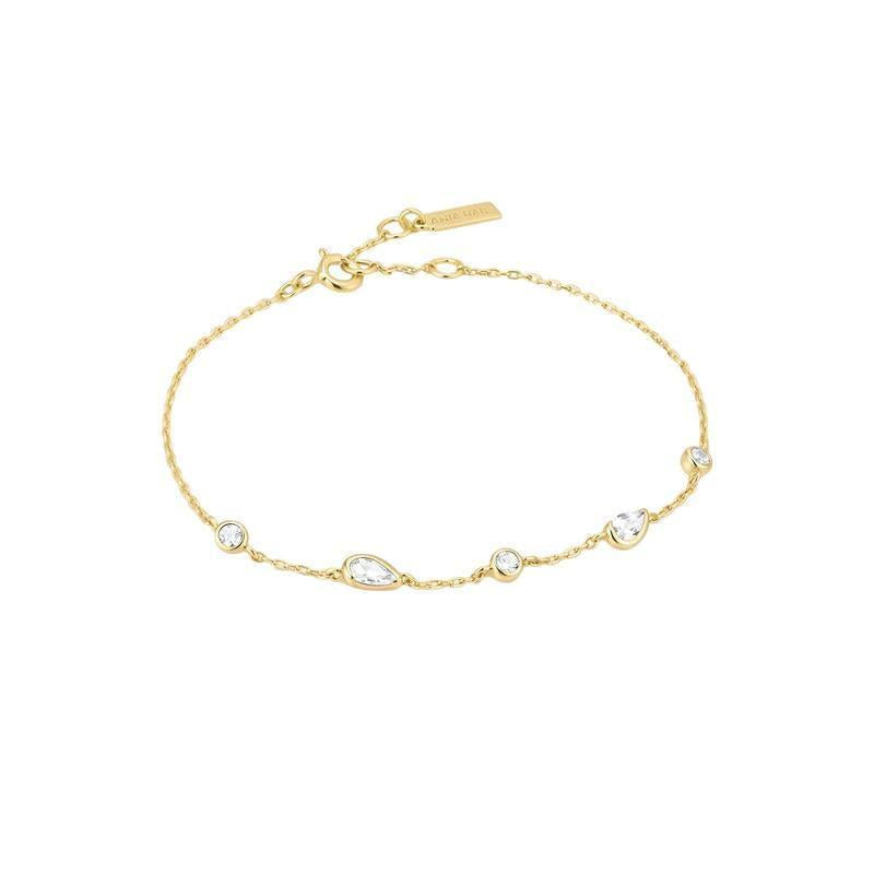 A delicate gold chain bracelet with five clear teardrop and round gemstones, displayed on a clean white background.