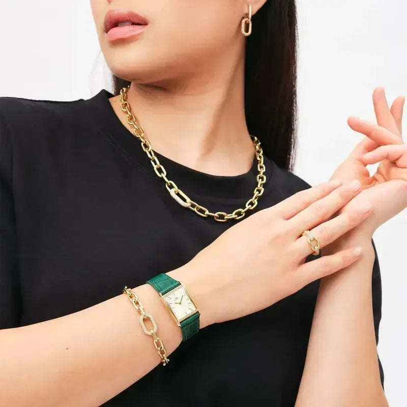 Daniel Wellington Bound watch with a gold rectangular case, champagne dial, and emerald green crocodile leather strap.