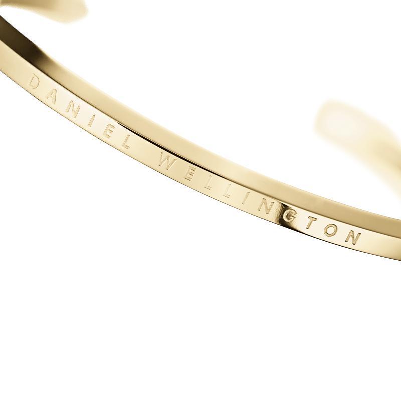 Minimalist gold-tone stainless steel Daniel Wellington classic cuff bangle with engraved logo branding.