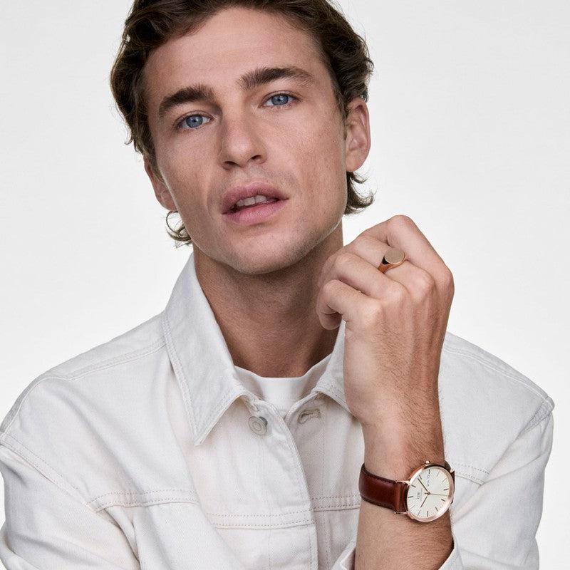Daniel Wellington Classic watch with rose gold case, champagne dial, and brown St Mawes leather strap on a man's wrist.