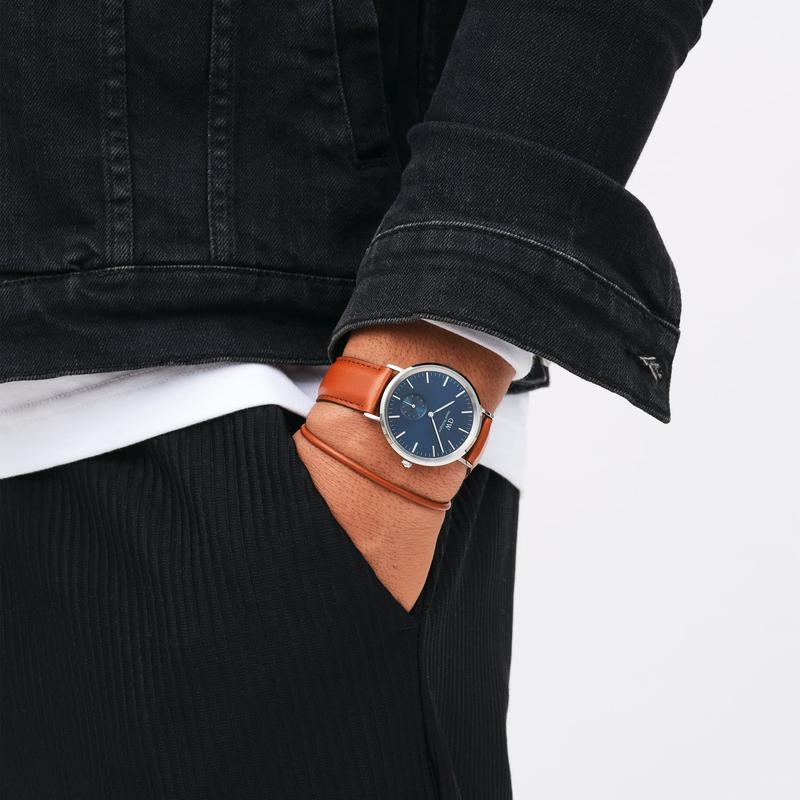 Daniel Wellington Classic Multi-Eye watch with a blue dial, silver stainless steel case, and brown leather strap on a wrist.