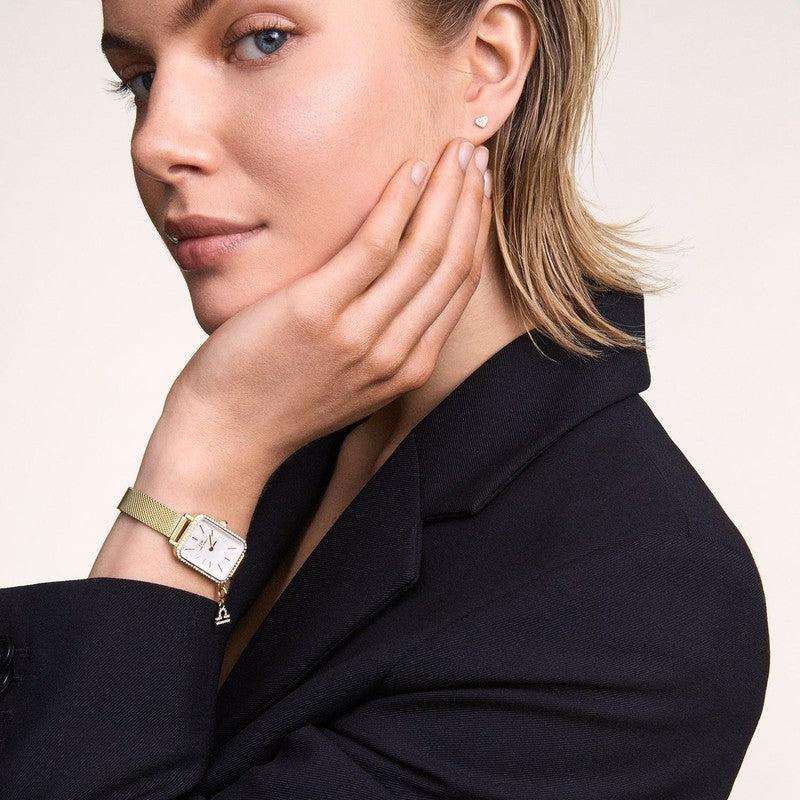 Elegant gold Daniel Wellington crystal heart stud earrings featuring a delicate 4.2mm claw-set design on a model.