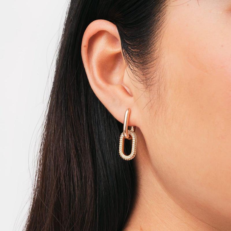 Chunky rose gold plated brass link earrings featuring sparkling crystal details worn on an ear.