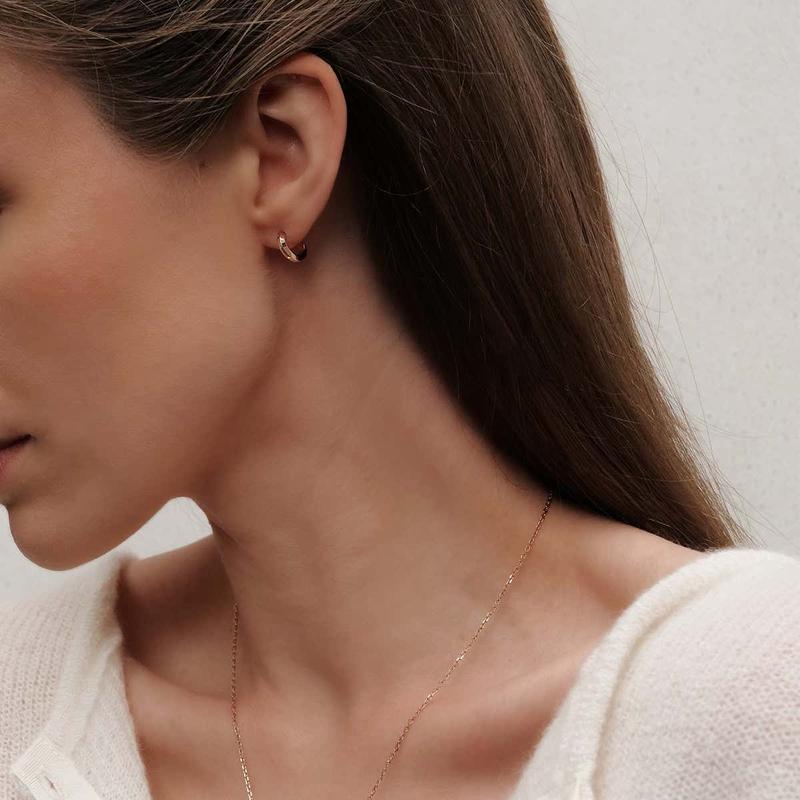 Minimalist Daniel Wellington Elan hoop earrings in rose gold-plated stainless steel worn on a model.