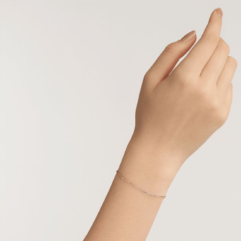Elegant Daniel Wellington Elan flat chain bracelet in rose gold-plated stainless steel worn on a wrist.