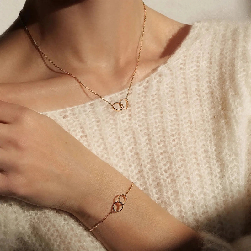 Elegant rose gold Daniel Wellington Elan Unity bracelet and matching necklace featuring delicate interlocking rings.