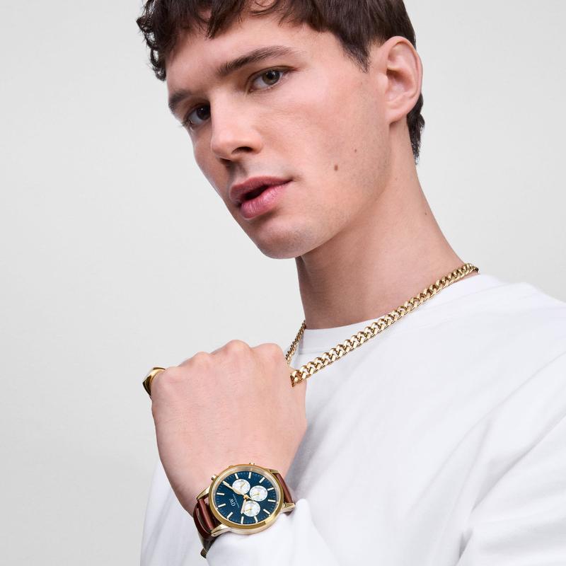 Polished gold-plated stainless steel Cuban link necklace worn by a man with a matching gold Daniel Wellington watch.