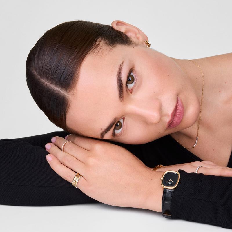 Daniel Wellington Margot watch featuring a sleek onyx ceramic dial, gold-tone case, and black leather strap on a model.