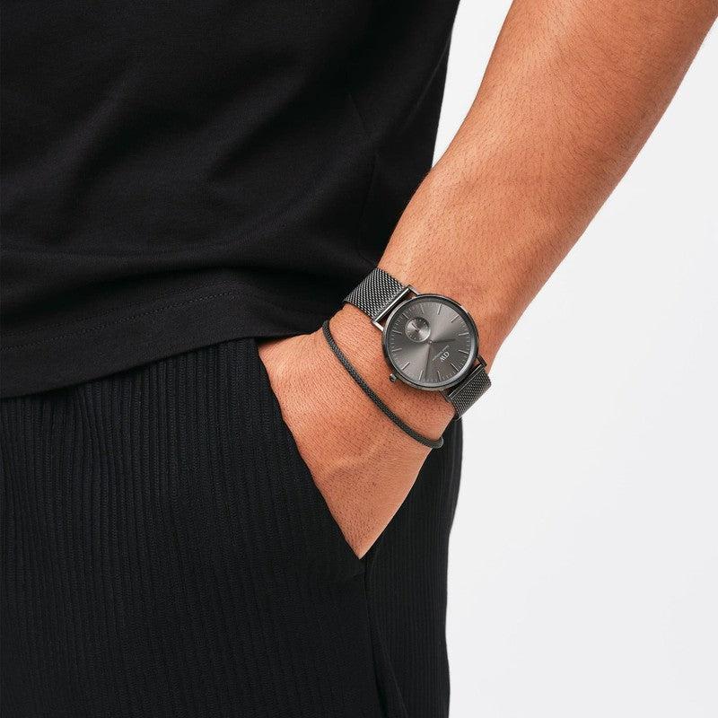 Daniel Wellington graphite stainless steel mesh bracelet paired with a matching black watch on a wrist.