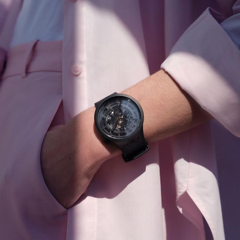 Swatch C-BLACK watch in matte black bioceramic with a bold transparent dial and sleek bio-sourced strap on a wrist.