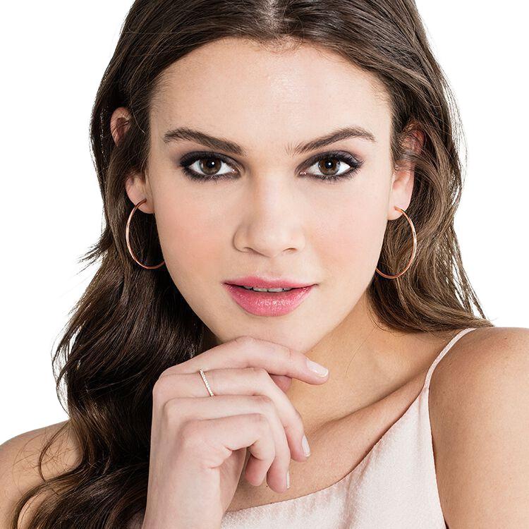 Delicate 18k rose gold plated midi ring featuring dazzling white zirconia stones on a woman's finger.